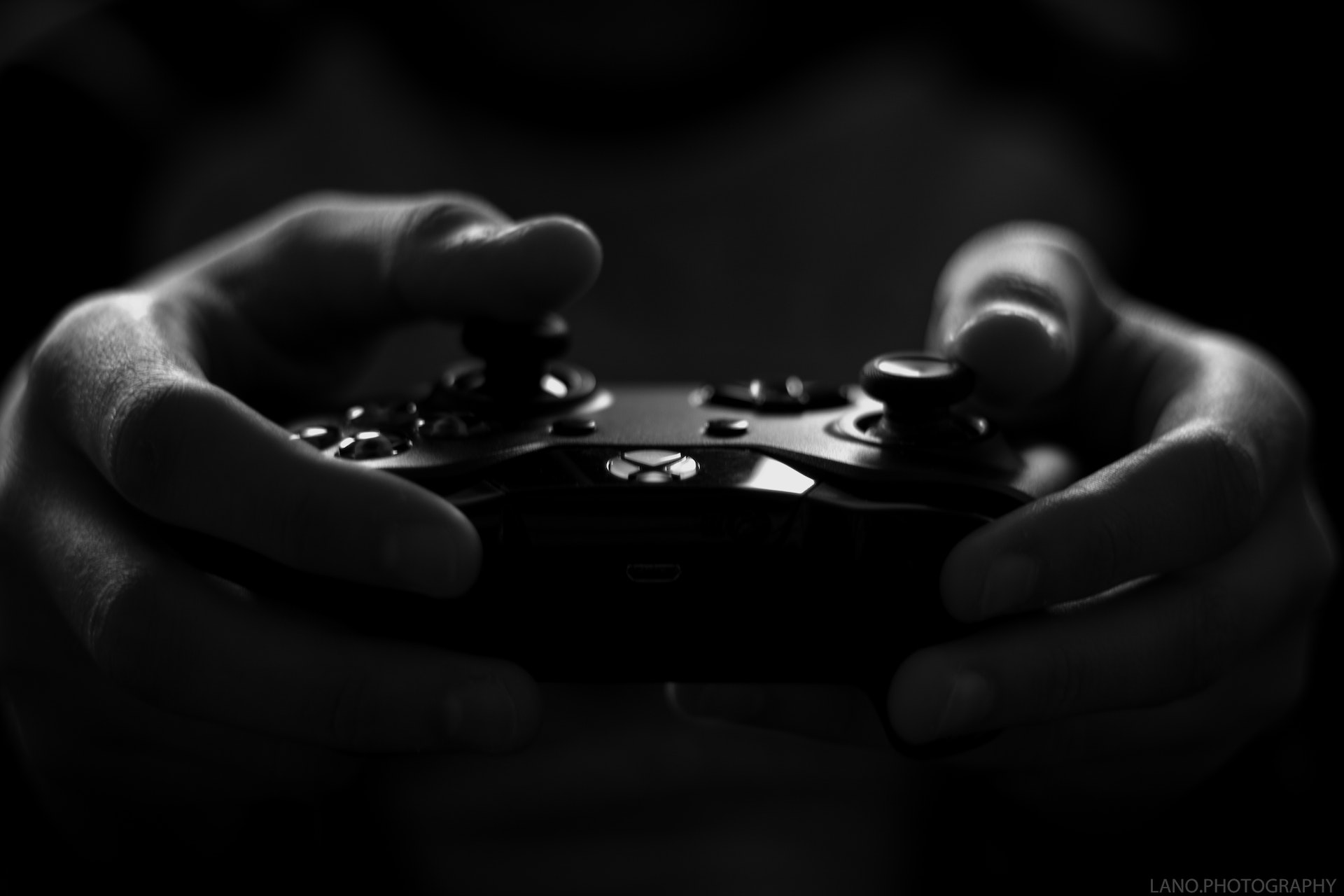Black and white close-up of hands holding Xbox controller.